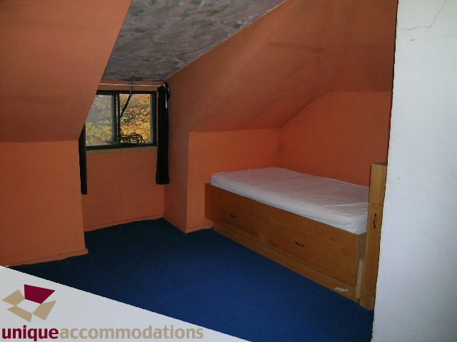 Attic bedroom with sloped ceiling, orange walls, and a small window. - 782 W 22nd Ave, Vancouver West Side