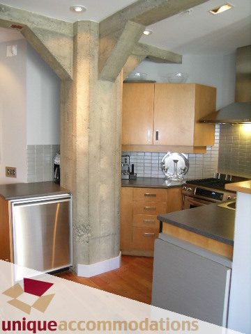 Bright kitchen with stainless steel appliances, hardwood floors, and exposed concrete beams. - 211- 1216 Homer, Vancouver Downtown