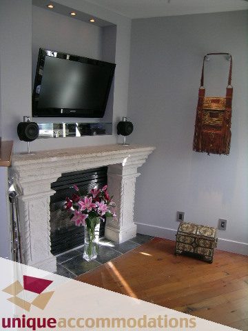 Furnished living room with marble fireplace, hardwood floors, and a flat-screen TV above the mantel. - 211- 1216 Homer, Vancouver Downtown