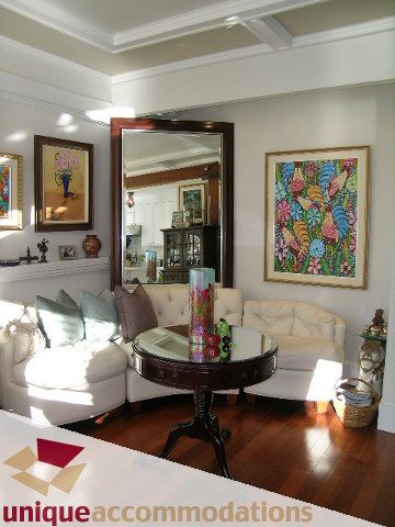 Furnished living room with hardwood floors, large mirror, and colorful artwork. - 47-777 Burrard Street, Vancouver Downtown