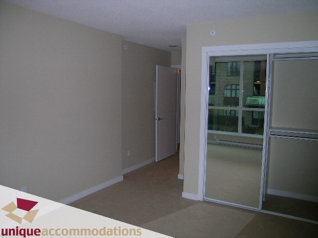 Living room with sliding glass doors leading to a balcony, showing a city view. - 179 Milross Rd., Vancouver Downtown