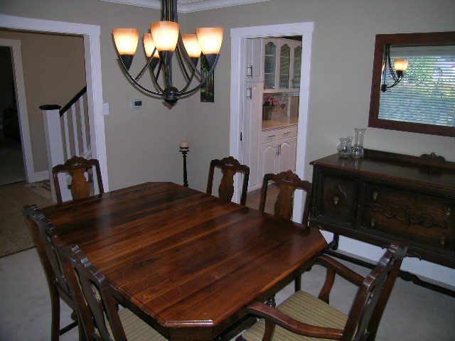 Spacious dining room with hardwood floors, a large wooden table, and a chandelier, perfect for entertaining.