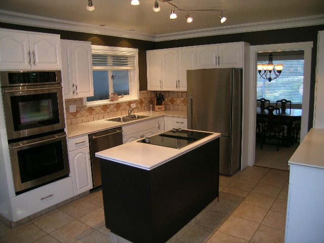 Modern kitchen with white cabinetry, stainless steel appliances, and a tiled backsplash. - 3554 St. Andrews Avenue, North Vancouver