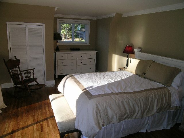 Spacious bedroom with natural light, white furniture, and a cozy rocking chair. - 3554 St. Andrews Avenue, North Vancouver