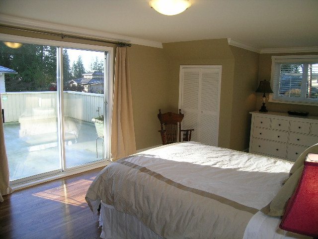 Spacious bedroom with large windows, hardwood floors, and a cozy bed setup. - 3554 St. Andrews Avenue, North Vancouver