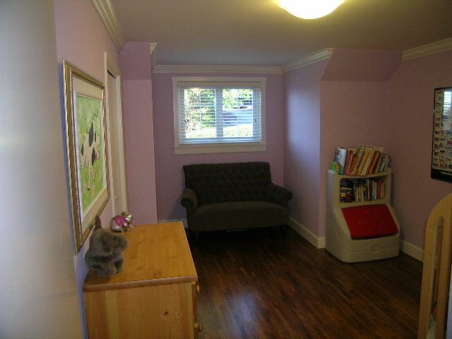 Spacious living room with hardwood floors, bookshelves, and a cozy corner. - 3554 St. Andrews Avenue, North Vancouver