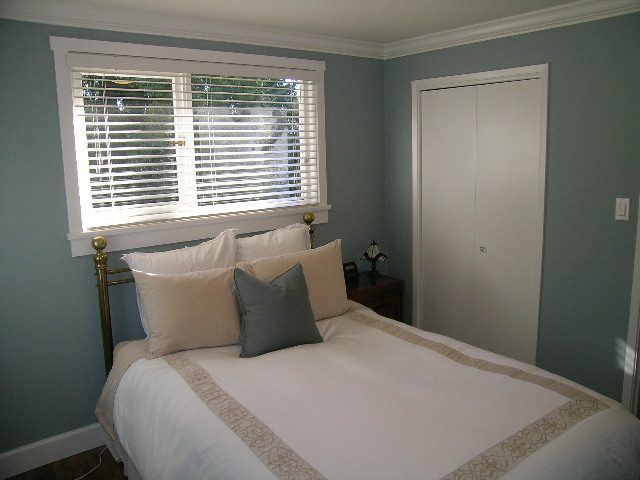 Spacious bedroom with a large window, white bedding, and a cozy ambiance. - 3554 St. Andrews Avenue, North Vancouver