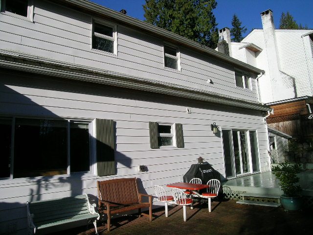 Furnished patio with wooden bench, red chairs, and white table, perfect for outdoor relaxation. - 3554 St. Andrews Avenue, North Vancouver