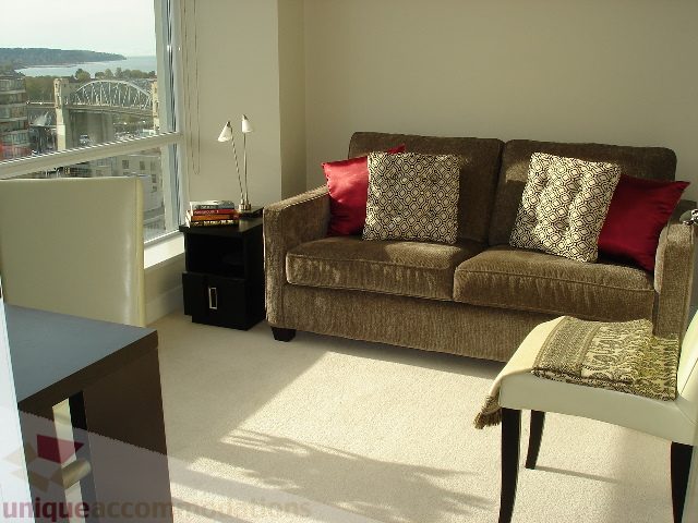 Bright living room with city view and modern furniture, featuring a comfortable sofa and armchair set. - 1504 - 1455 Howe Street, Vancouver Downtown