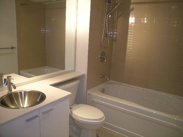 Modern bathroom with sleek countertop, large bathtub, and shower. - 3309-111 W Georgia, Vancouver Downtown