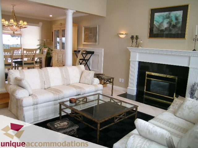 Furnished living room with white couches, black coffee table, and fireplace. - 4139 Quarry Court, North Vancouver