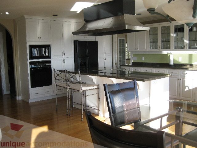 Bright kitchen with white cabinetry, granite countertops, and hardwood floors. - 4139 Quarry Court, North Vancouver