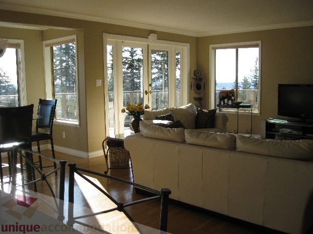 Bright living room with large windows, hardwood floors, and a city view. - 4139 Quarry Court, North Vancouver