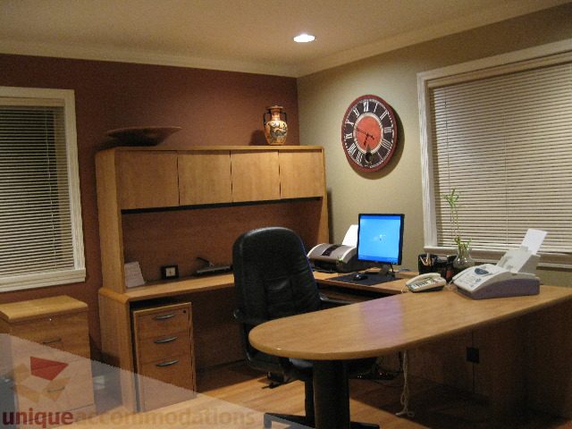Furnished office space with wooden cabinets, desk, and clock, hardwood floors. - 4139 Quarry Court, North Vancouver