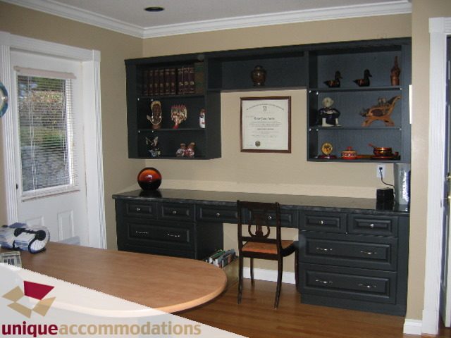 Furnished den with dark wood cabinets, framed certificate, and decorative items. - 4139 Quarry Court, North Vancouver