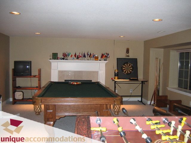 Game room with pool table, foosball table, and mounted TV. - 4139 Quarry Court, North Vancouver