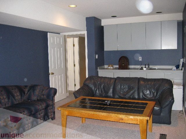 Living room with dark blue walls, leather couches, and a wooden coffee table. - 4139 Quarry Court, North Vancouver