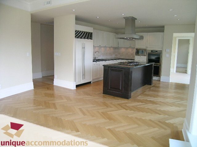Bright kitchen with white cabinetry, black countertops, and hardwood floors. - PH1 - 508 Waters Edge Cres., West Vancouver