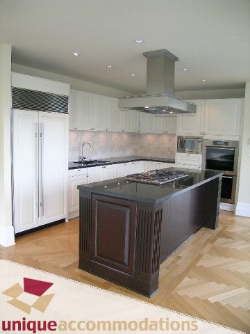 Bright kitchen with black countertops, hardwood floors, and stainless steel appliances. - PH1 - 508 Waters Edge Cres., West Vancouver