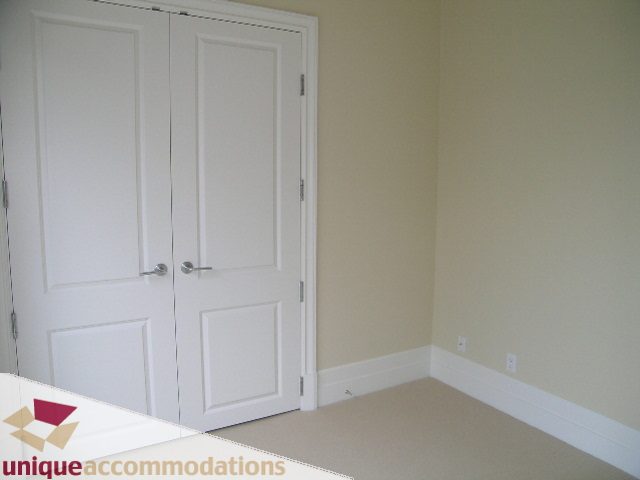 Furnished bedroom with white closet doors and beige carpet. - PH1 - 508 Waters Edge Cres., West Vancouver