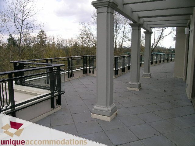 Spacious balcony with stone flooring and elegant columns, offering a serene outdoor space. - PH1 - 508 Waters Edge Cres., West Vancouver