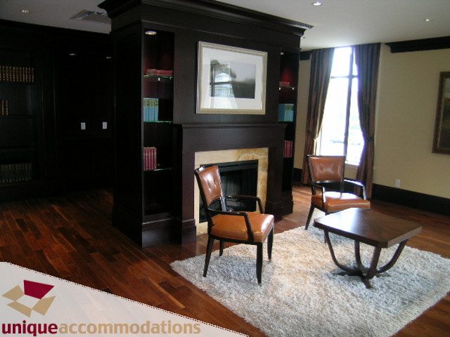Furnished living room with hardwood floors, a fireplace, and a large window. - PH1 - 508 Waters Edge Cres., West Vancouver