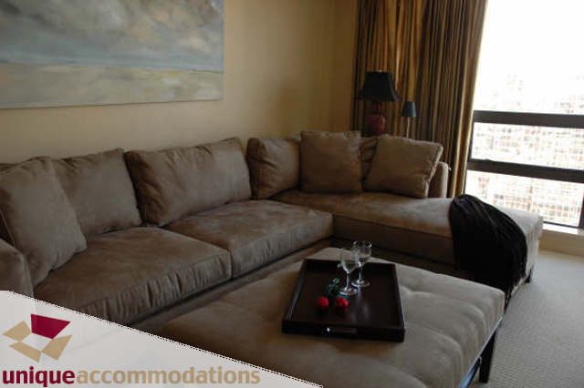 Furnished living room with large sectional sofa, city view, and modern decor. - 2314 - 938 Smithe Street, Vancouver Downtown