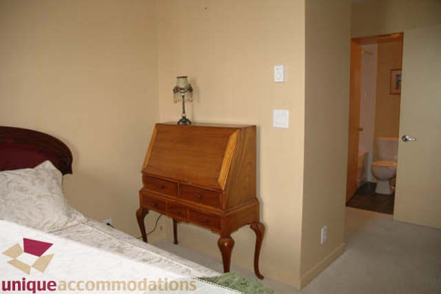 Furnished bedroom with wooden desk and bed, neutral decor. - 2314 - 938 Smithe Street, Vancouver Downtown