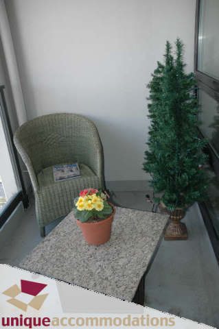 Bright living area with wicker chair, potted flowers, and artificial tree. - 2314 - 938 Smithe Street, Vancouver Downtown