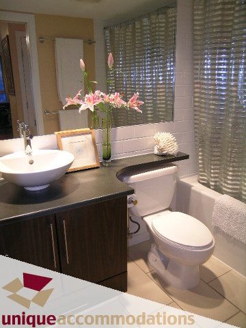Furnished bathroom with modern sink, dark countertop, and white toilet. - 1006-1225 Richards Street, Vancouver Downtown