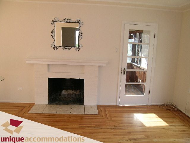 Living room with hardwood floors, fireplace, and French door leading to balcony. - 1428 29th Street, West Vancouver