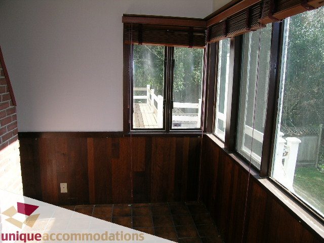 Bright sunroom with large windows, wood paneling, and tiled floor. - 1428 29th Street, West Vancouver