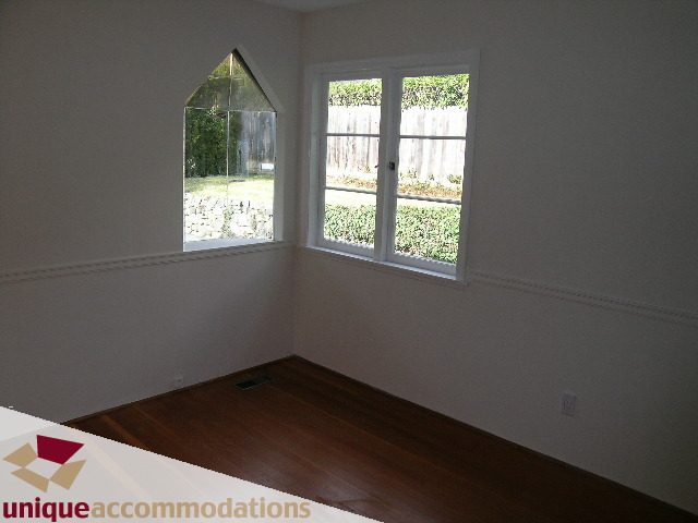 Den with hardwood floors and large windows, offering a view of the backyard. - 1428 29th Street, West Vancouver