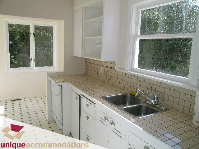 Bright kitchen with white cabinets, tiled backsplash, and large windows showing greenery. - 1428 29th Street, West Vancouver