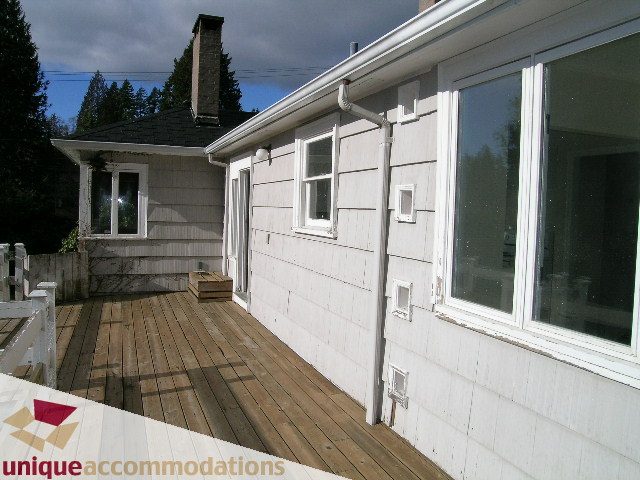 Bright deck with wooden flooring and large windows, leading to a cozy 2-bedroom + den house. - 1428 29th Street, West Vancouver