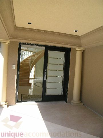 Entryway with glass doors leading to a staircase, beige walls, and decorative columns. - 4215 Evergreen Ave, West Vancouver