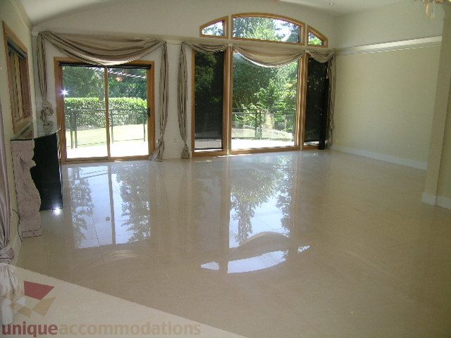 Spacious living room with glossy tile floors and large windows. - 4215 Evergreen Ave, West Vancouver