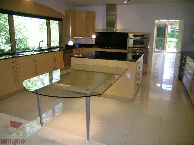 Bright kitchen with sleek black countertops and modern appliances, featuring a large island and glossy tiled floor.