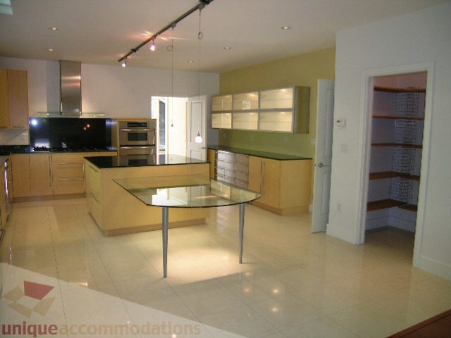 Bright kitchen with modern appliances, glass dining table, and light wood cabinets. - 4215 Evergreen Ave, West Vancouver