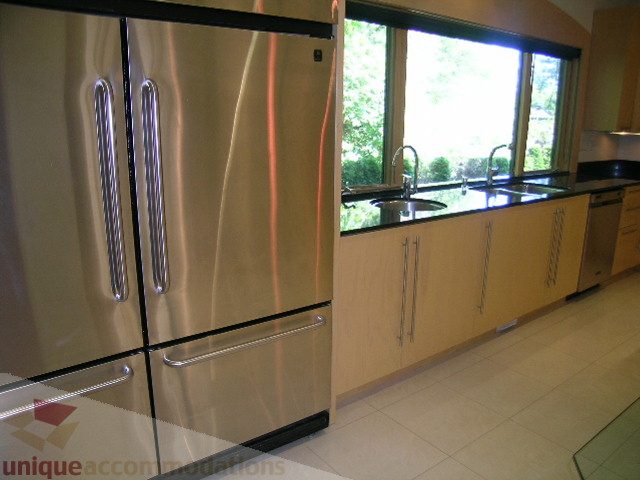 Bright kitchen with stainless steel appliances, granite countertops, and a view of greenery outside. - 4215 Evergreen Ave, West Vancouver