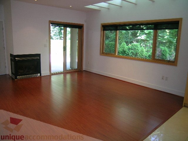 Bright living room with hardwood floors and large windows overlooking greenery. - 4215 Evergreen Ave, West Vancouver