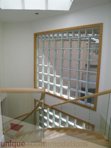 Staircase with glass block wall and wooden railings, natural light. - 4215 Evergreen Ave, West Vancouver