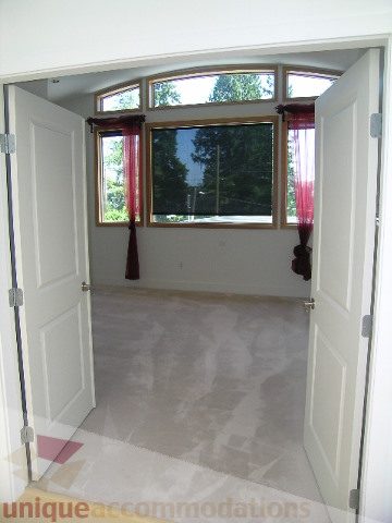 Bright sunroom with large arched window, marble floor, and red curtains. - 4215 Evergreen Ave, West Vancouver