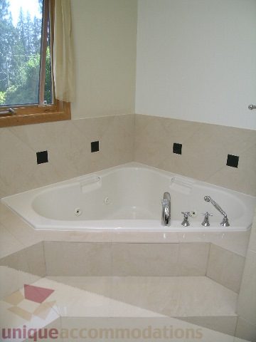 Bathroom with corner tub, beige countertops, and window view. - 4215 Evergreen Ave, West Vancouver
