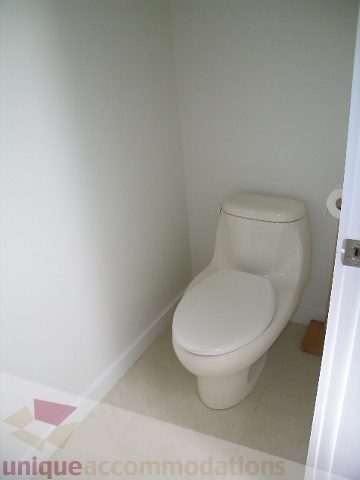 Small, clean bathroom with white toilet and beige carpet. - 4215 Evergreen Ave, West Vancouver