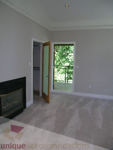 Bright living room with hardwood floors and large windows, leading to a balcony. - 4215 Evergreen Ave, West Vancouver