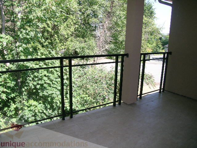 Spacious balcony with tiled floor and black railing, surrounded by lush greenery. - 4215 Evergreen Ave, West Vancouver