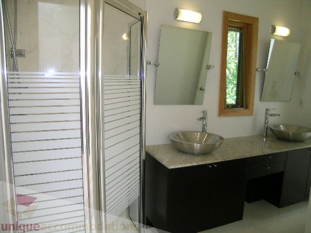 Bathroom with modern sink, frosted glass shower, and large mirror. - 4215 Evergreen Ave, West Vancouver