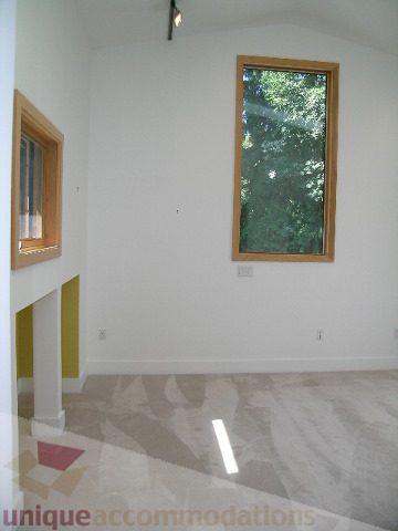 Bright living room with large window and white walls, carpeted floor. - 4215 Evergreen Ave, West Vancouver