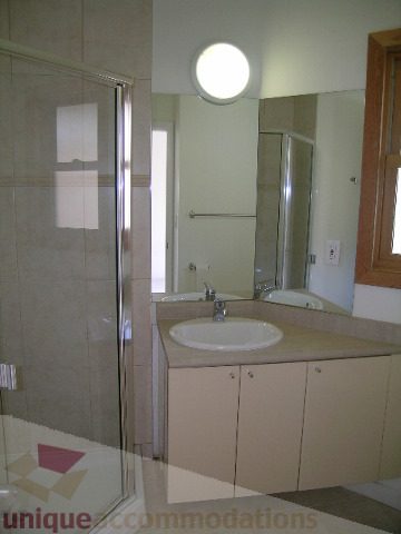 Bathroom with beige cabinets, countertop, and large mirror. - 4215 Evergreen Ave, West Vancouver